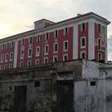 L�edificio, dall�ampia e rossa facciata scrostata, si innalza su cinque livelli scanditi da una lunga serie di finestre parallele, divise da due fasce bianche verticali che corrono lungo tutto il prospetto